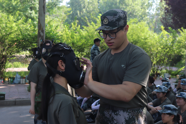 c3035d8b68bc4e089b444a582fbdeb6e.jpg 教官帮助学生穿戴防毒面具.JPG